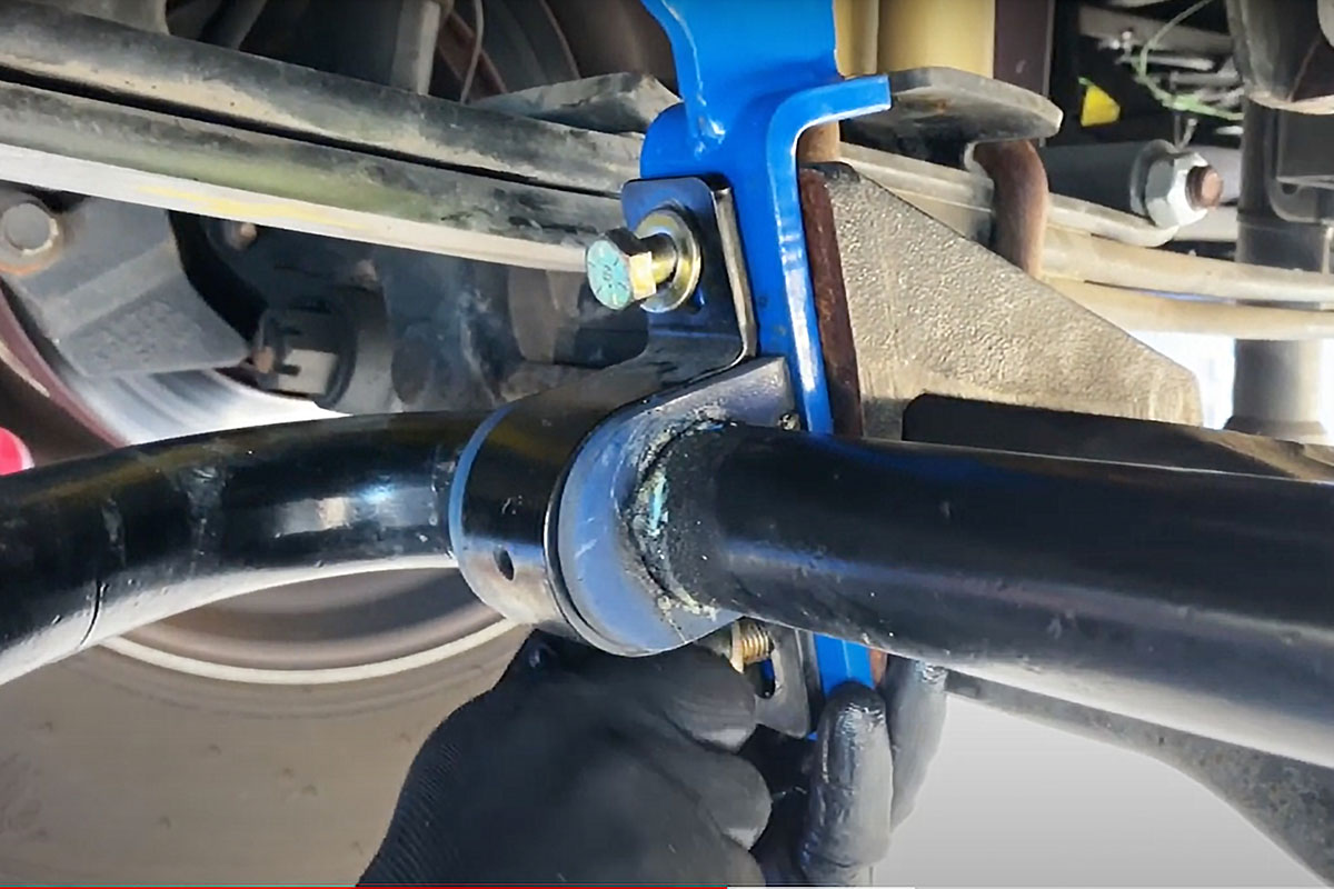 The four bolts that hold the front sway bar saddle bracket are loosened, then two on one side are removed
