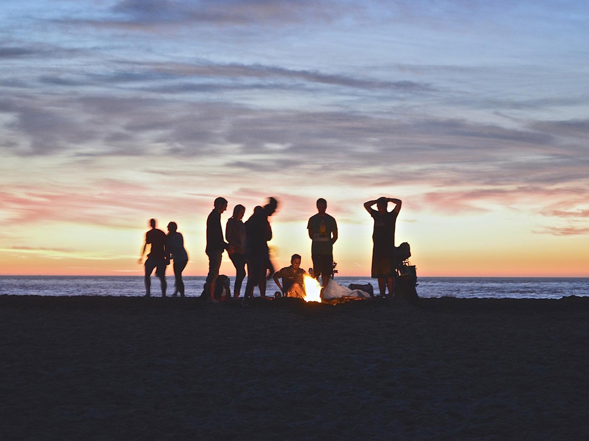 people standing around a fire a dusk