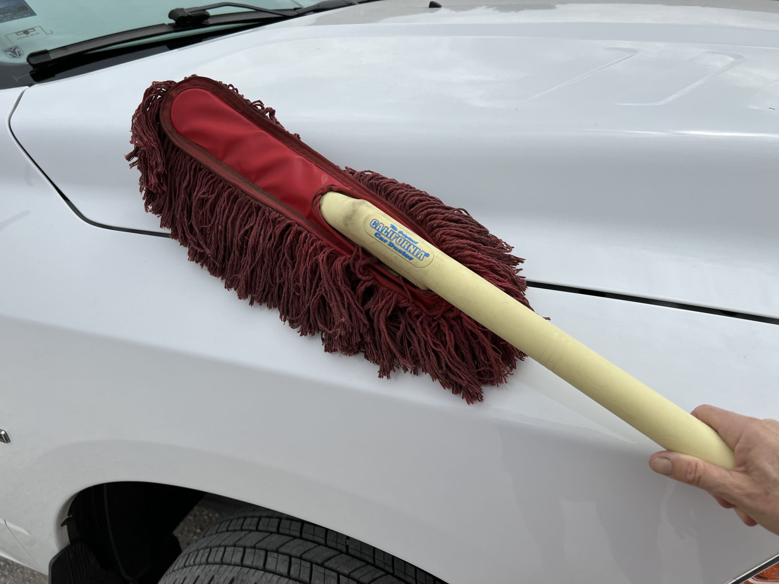 technician uses an original California Car Duster to wipe the surface of a car