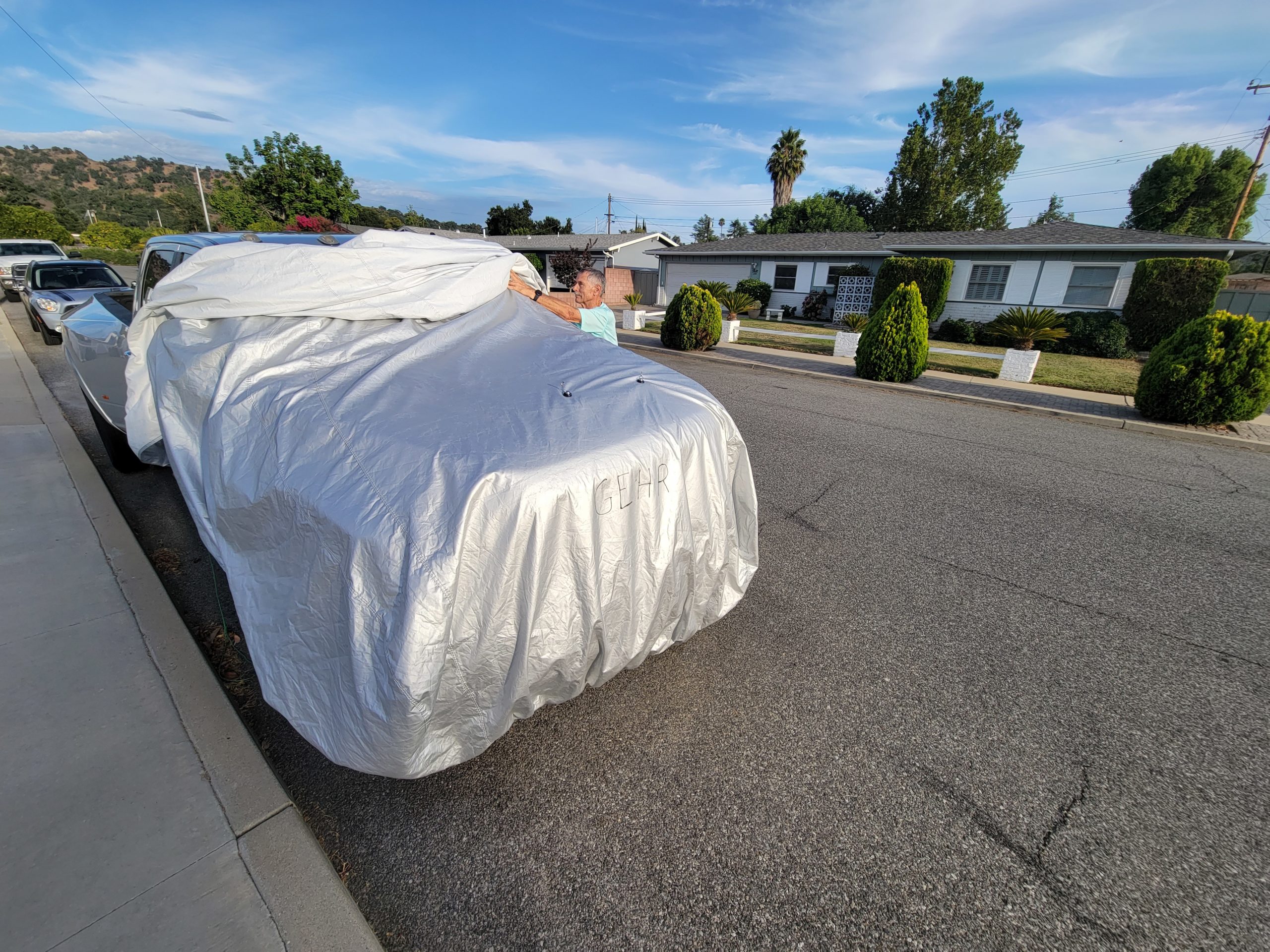 technician rolls out the rear portion of the car cover while the front is held with magnets