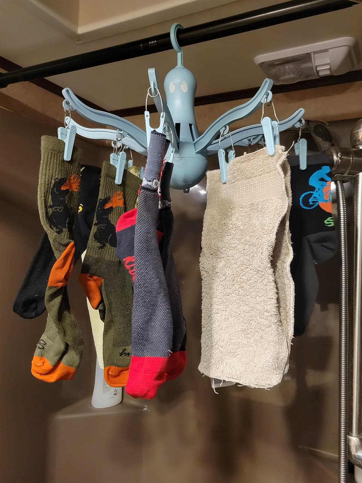 socks and towels are clipped to a hanging carousel drying device held by shower rod