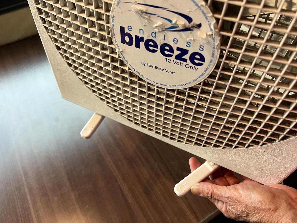 a hand adjusts one of the Endless Breeze fan legs