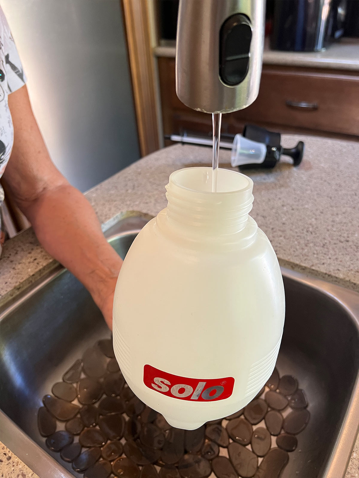 a Solo canister is filled with water from a faucet