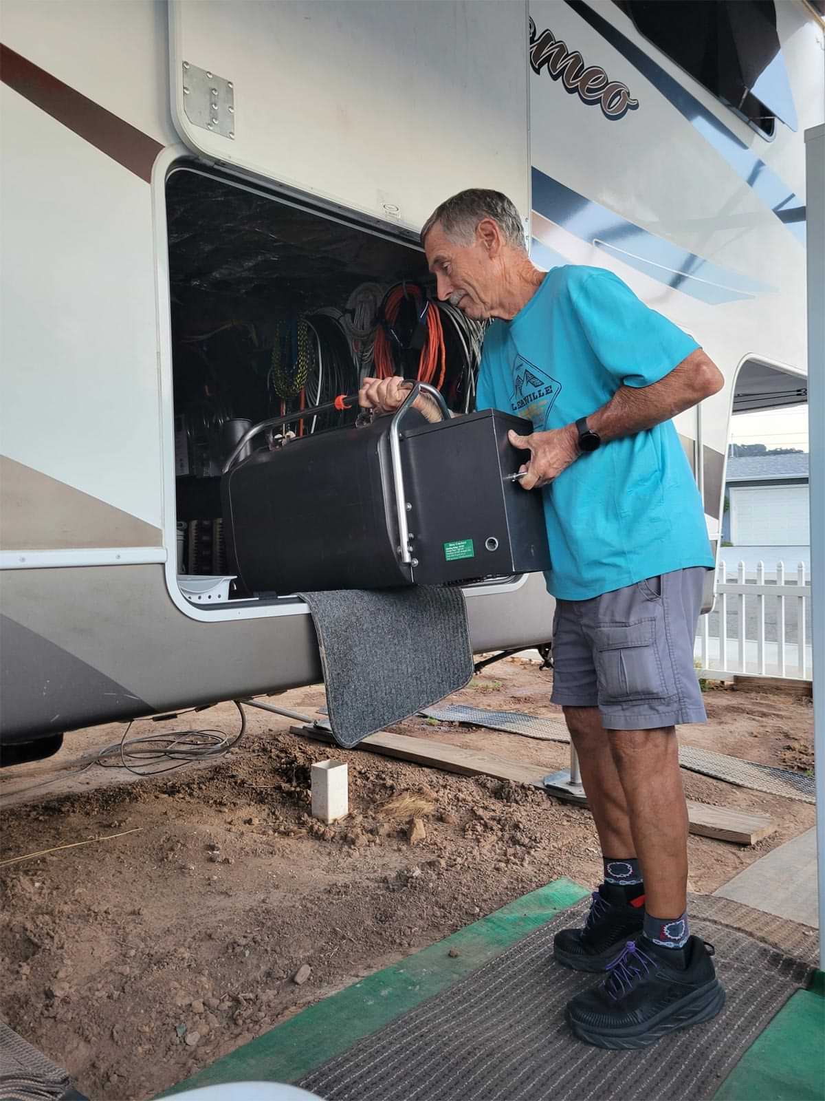 an RV technician removes a Green Mountain Davy Crockett model grill from storage on the outside of an RV