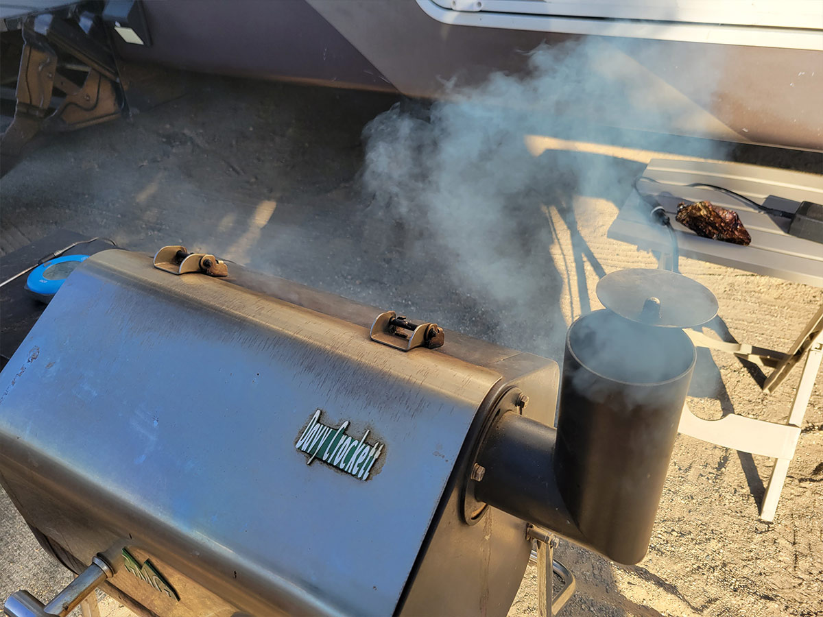 close view of the Davy Crockett model grill and its vent, releasing smoke