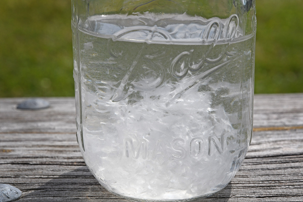 a mason jar filled with water and a single sheet of Thetford’s 1-ply toilet paper