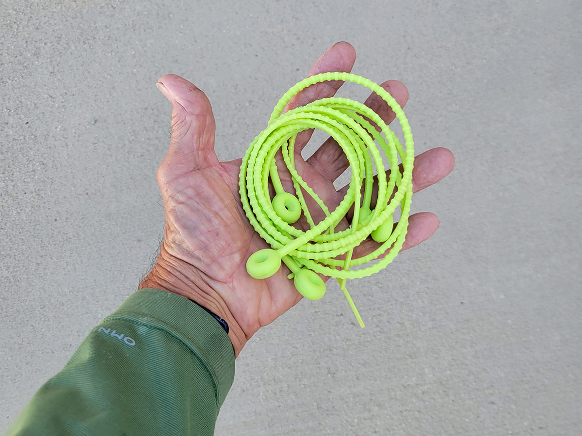 a hand holds a group of 21 inch neon green silicone zip ties