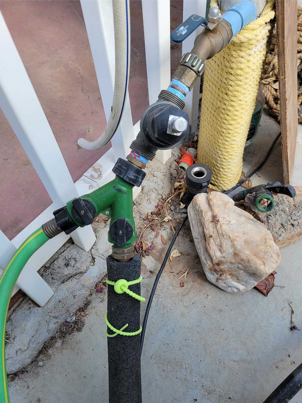 two neon green silicone zip ties secure insulation around a water hose