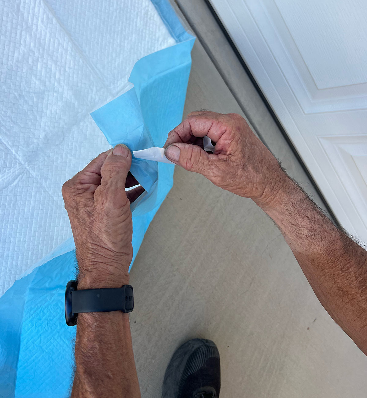 hands pull back an adhesive tab on the piddle pad corner