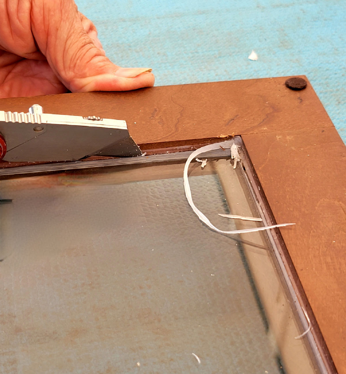 the silicone sealant holding the glass in place on the compartment door is carefully sliced with a razor knife