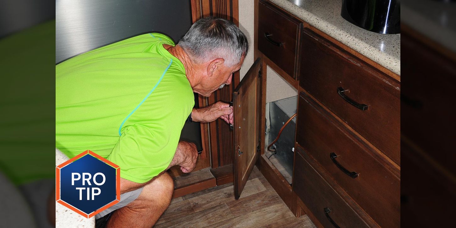 man looks into a cabinet under a counter