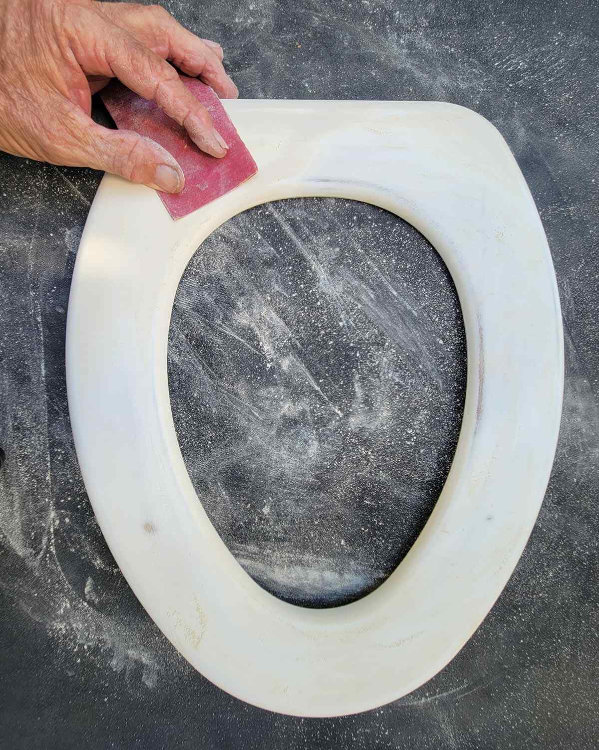 the toilet seat is sanded with 200-grit paper