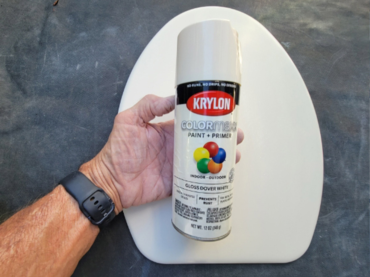 a hand holds a container of Krylon Dover White spray paint-and-primer