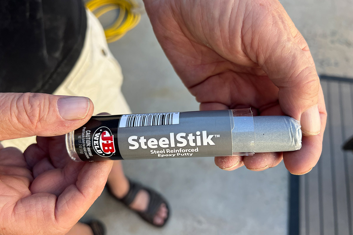 hands hold a open container of J-B Weld SteelStik
