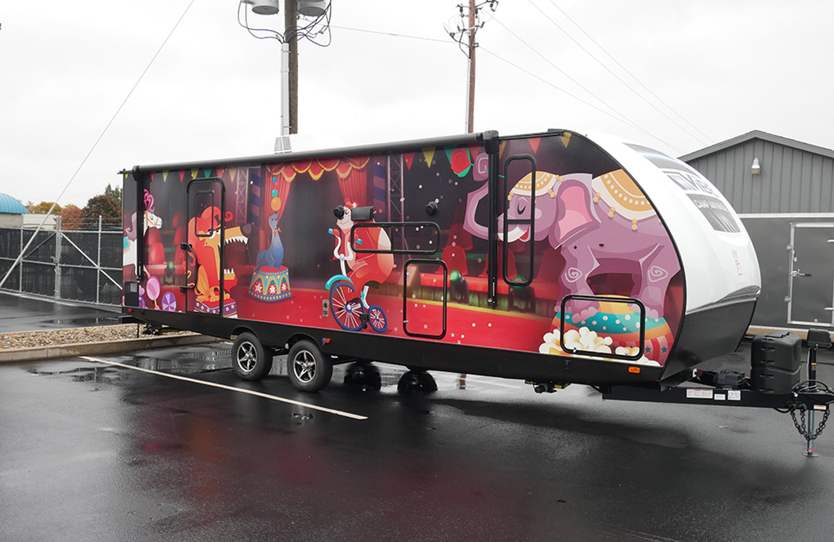 three quarter view of a travel trailer featuring a custom cartoon animal circus themed graphic wrap 