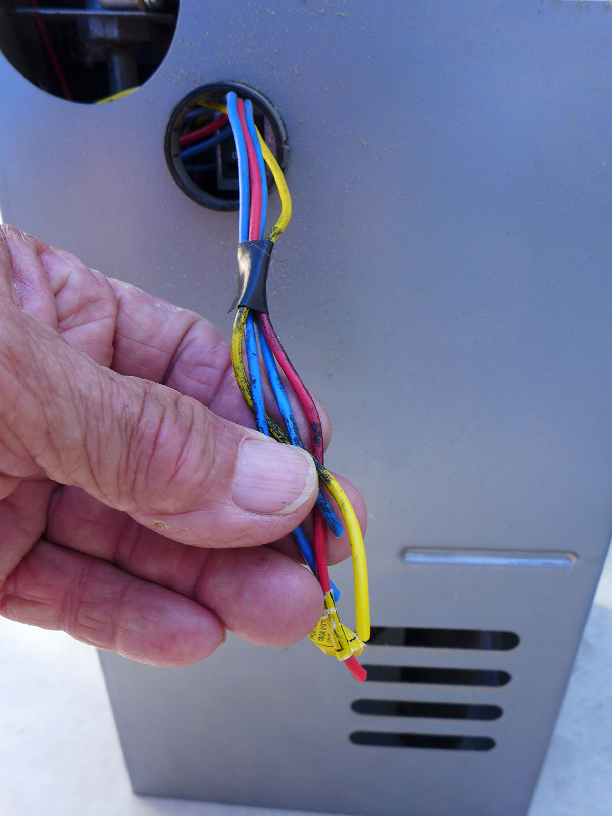 a hand holds a grouping of four wires; one red, one yellow and two blue