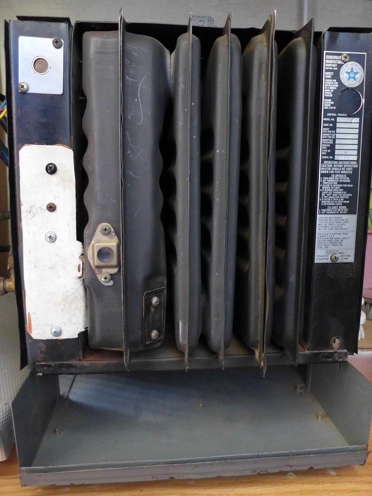 an older Suburban T-Series furnace with the front cover removed and the sight glass visible