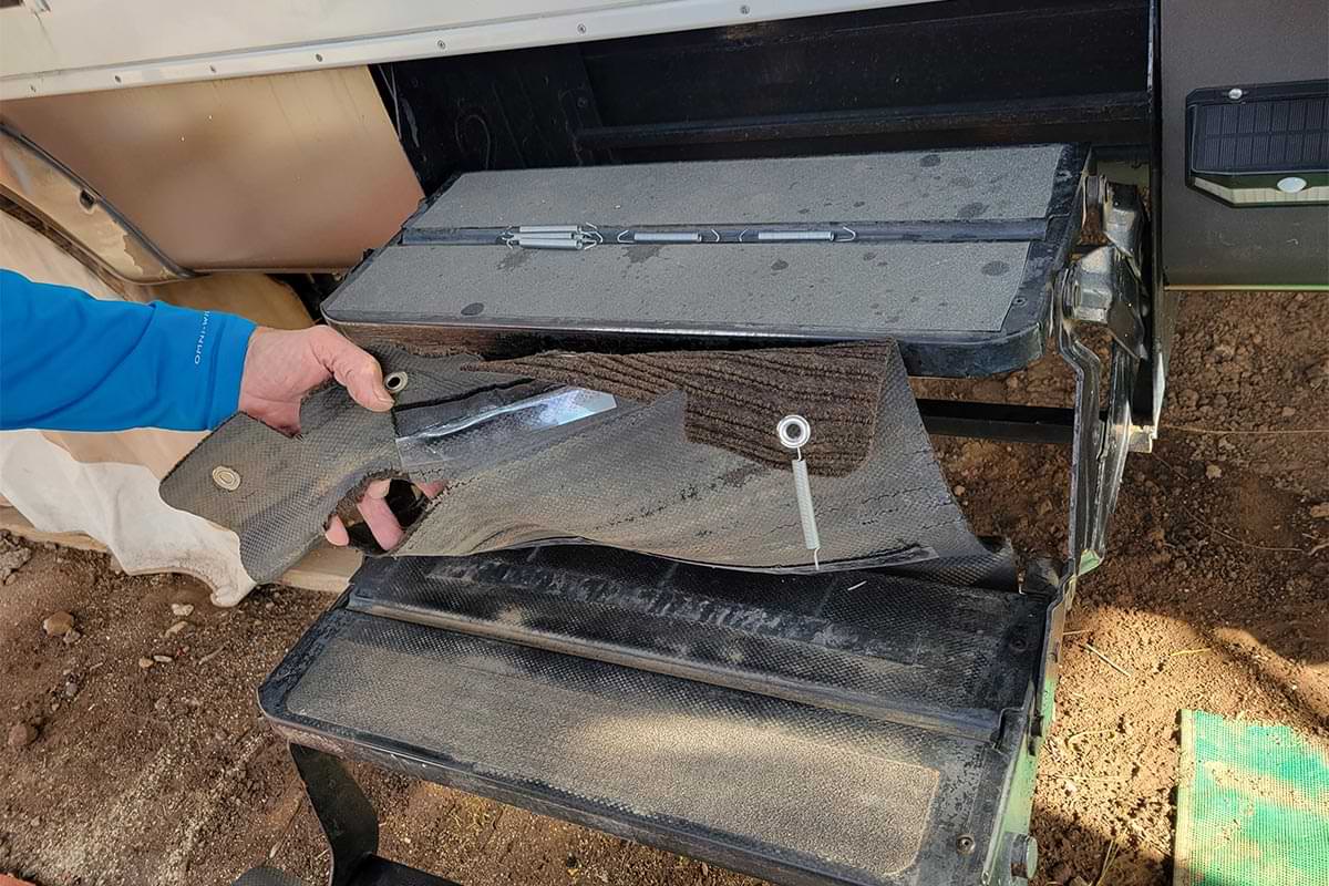 hands remove the old RV step covered, showing the spring fastener