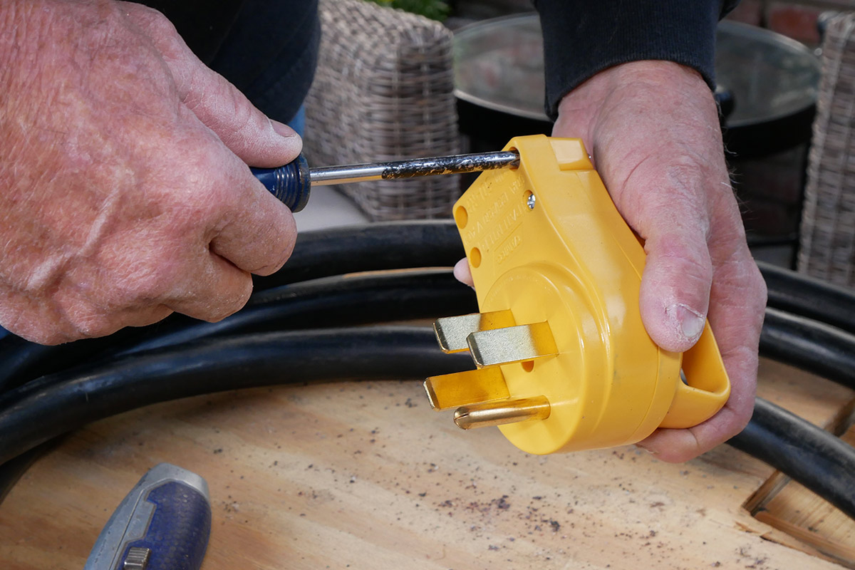 a screw is removed from the yellow two-piece plug using a screwdriver