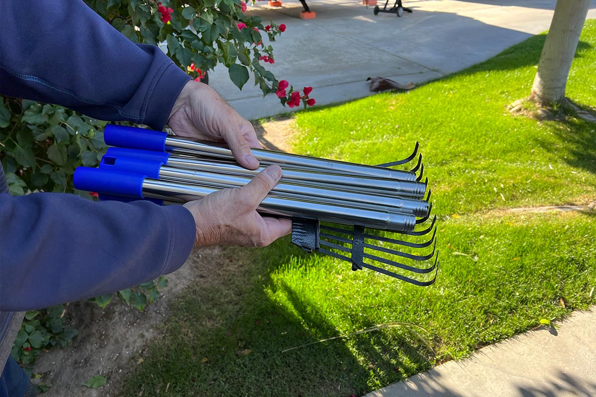 hands hold the four stainless-steel pole sections that when put together make the rake