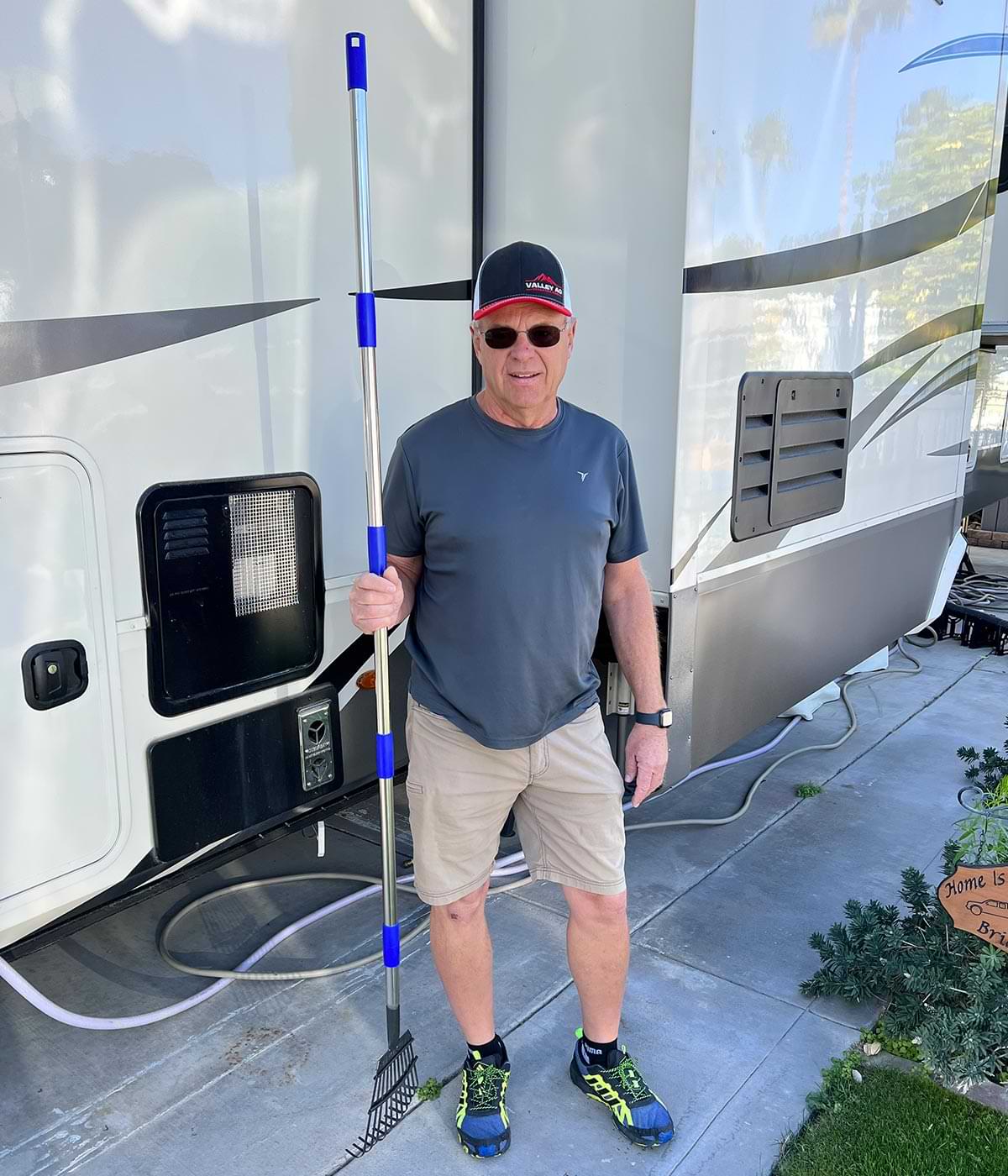 a man stands near an RV holding the rake vertical to demonstrate its length