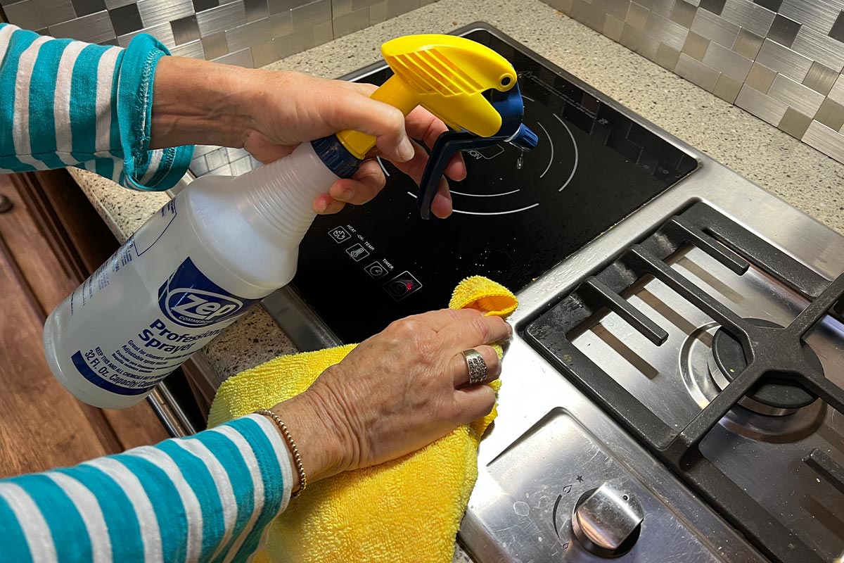 a spray bottle with Voom! cleaner and a microfiber towel are used to clean an RV stove top