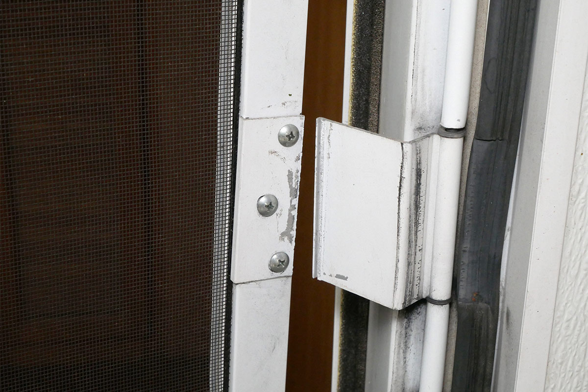 close view of an RV screen door hinge broken in two pieces