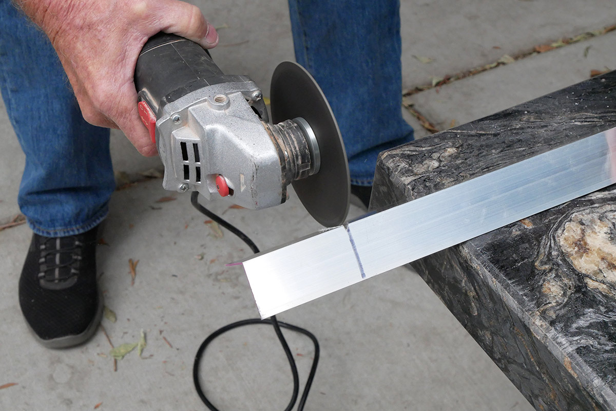 an angle grinder is used to cut the aluminum angle stock into three brackets