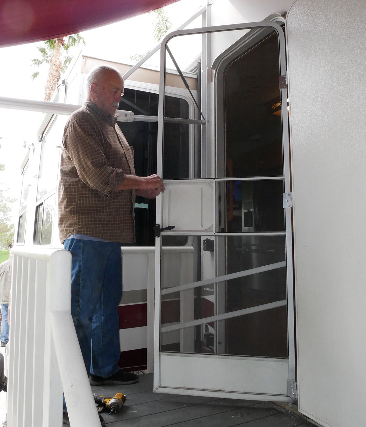 the RV technician opens and surveys the screen door movement with the newly attached brackets