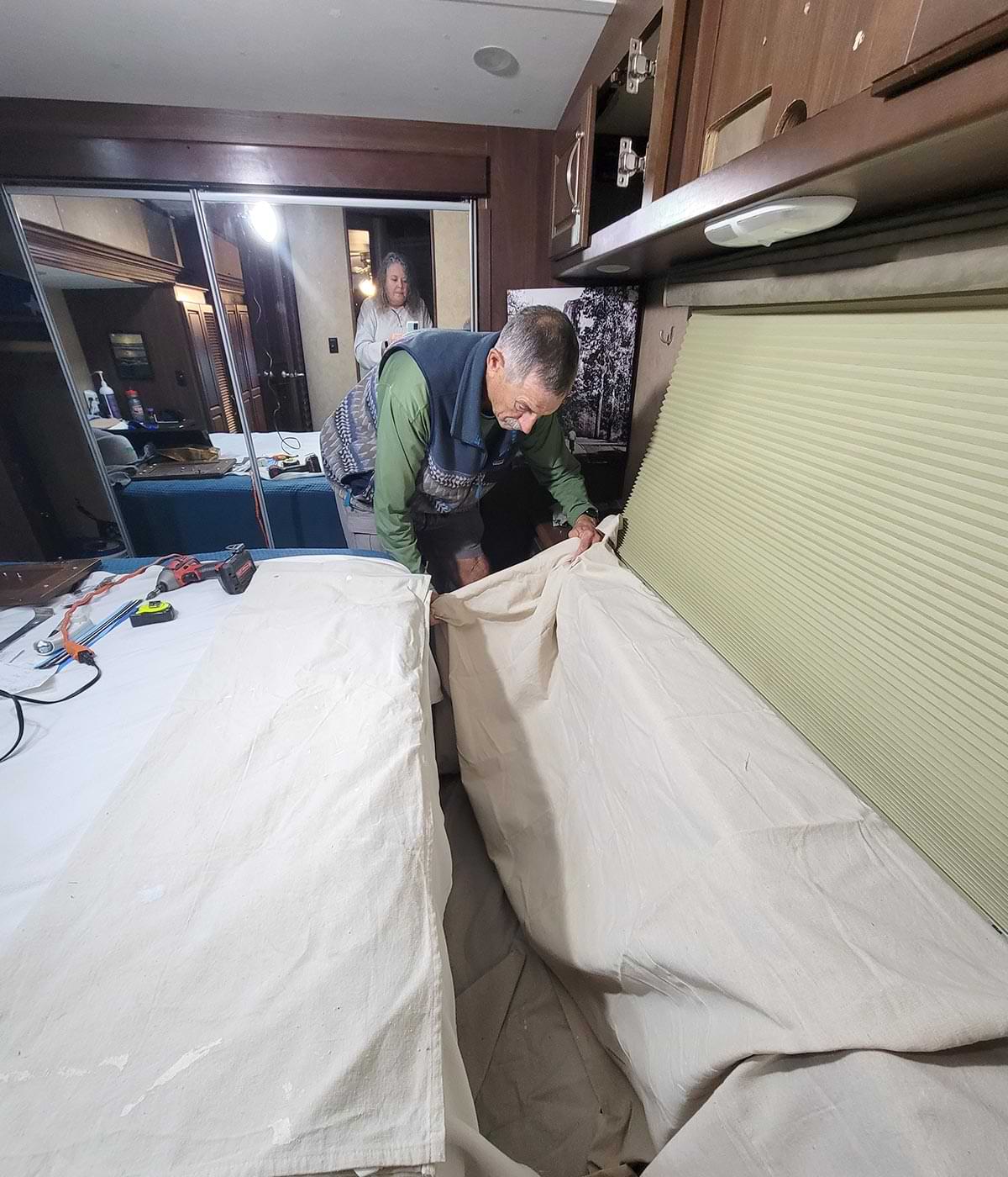 a man lays a painter's tarp on the floor under the intended work area