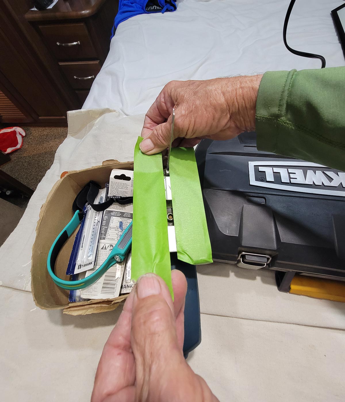 a hand pulls a piece of lime green painter's tape taut while covering the metal jigsaw foot