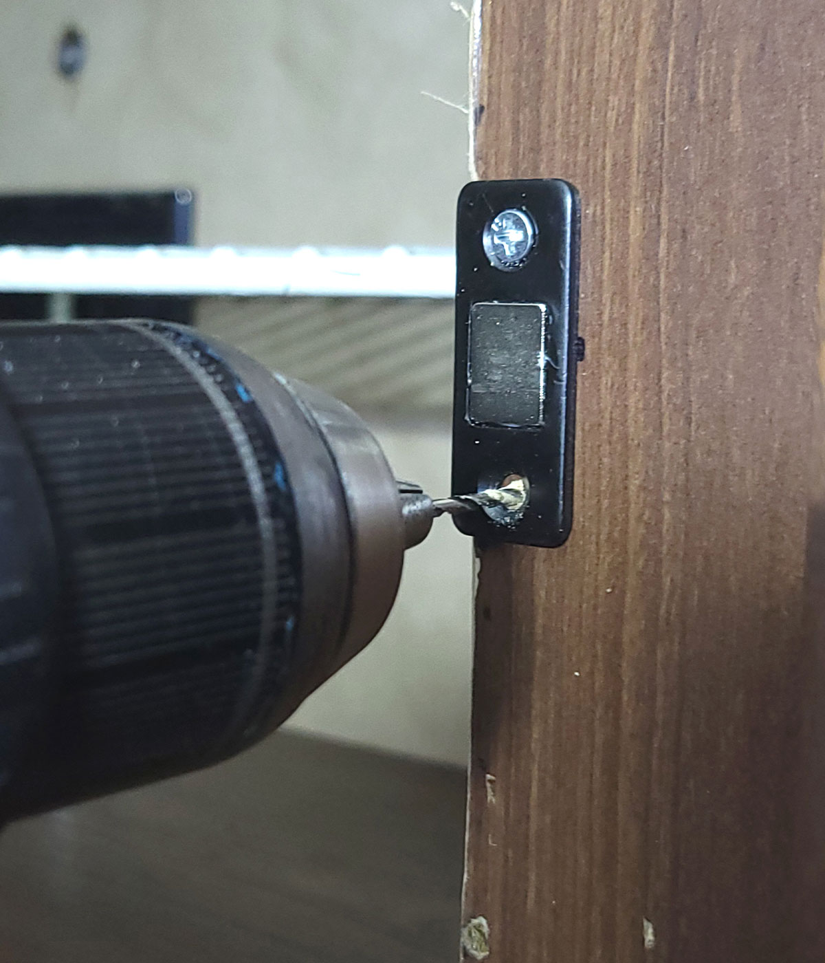 a magnetic catch is attached to the overhead compartment opening with enclosed screws