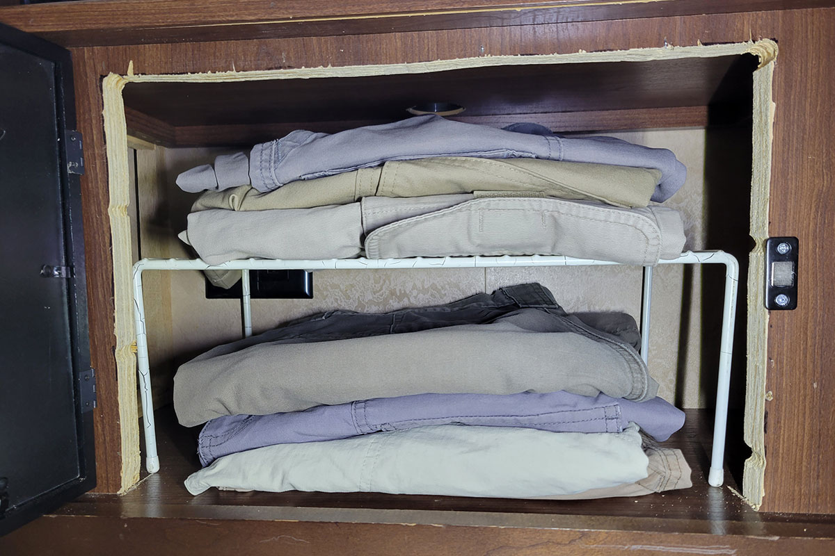 full view of the new storage compartment containing folded clothes stacked on a small rack