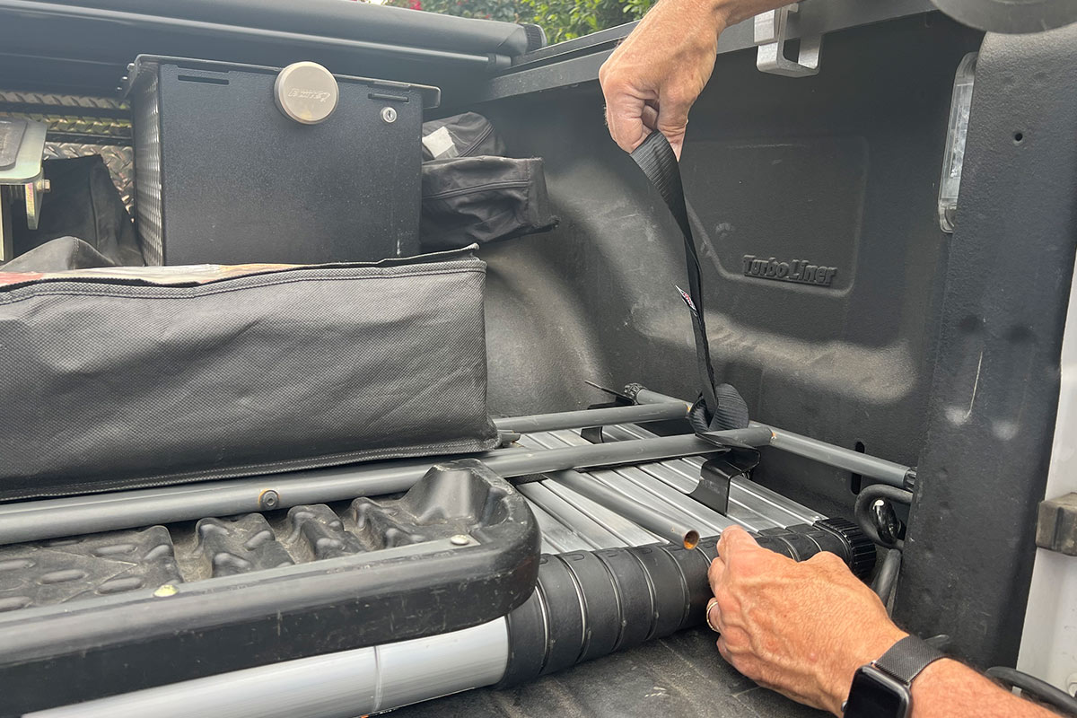 the extension strap is looped through the D-ring on one side of the truck bed