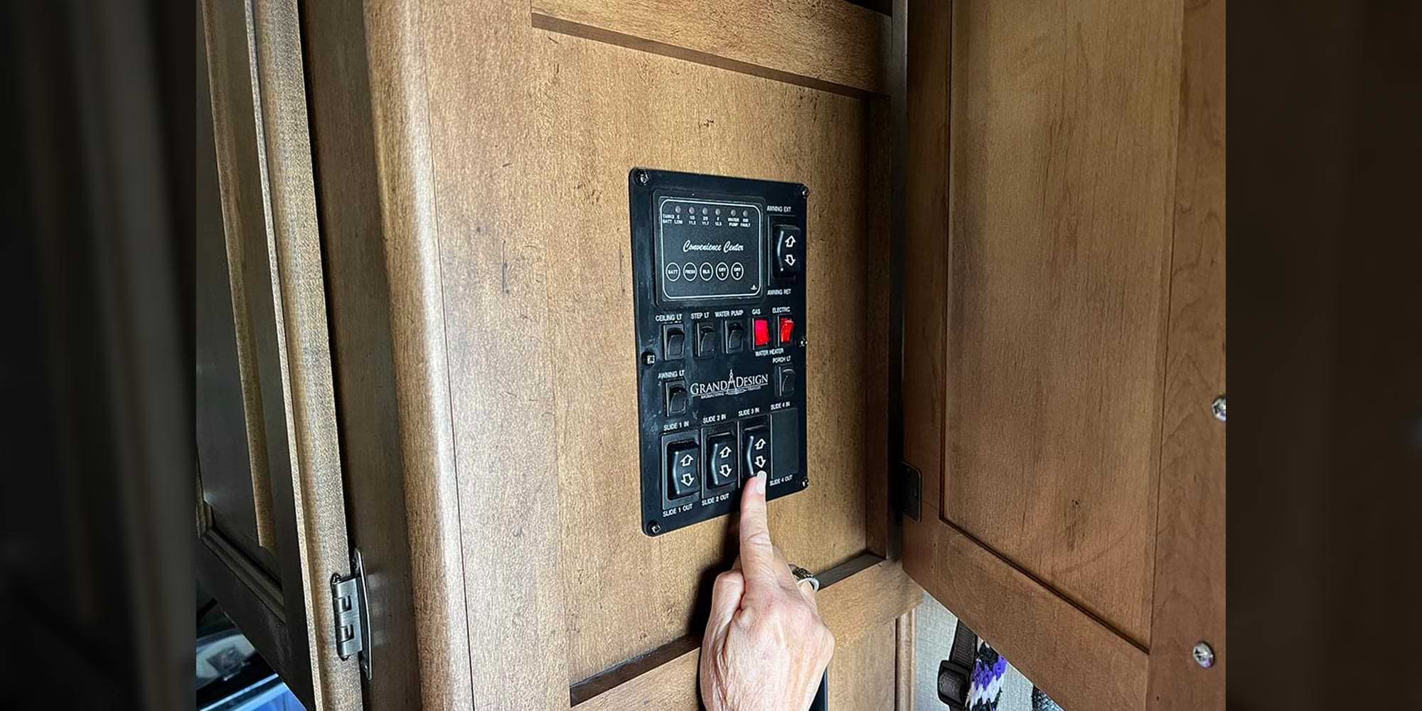 a woman's hand moves to activate a button on a wall control panel