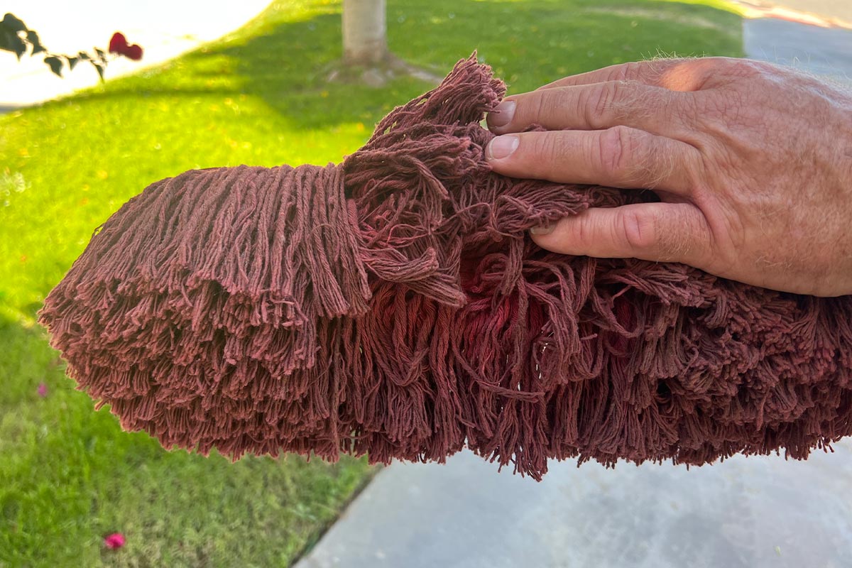 close view of a hand pulling back a section of the cotton mop head