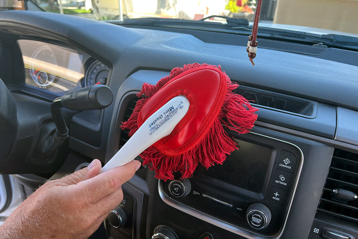 a hand uses the Mini Duster to wipe the dashboard screen of a Ram truck