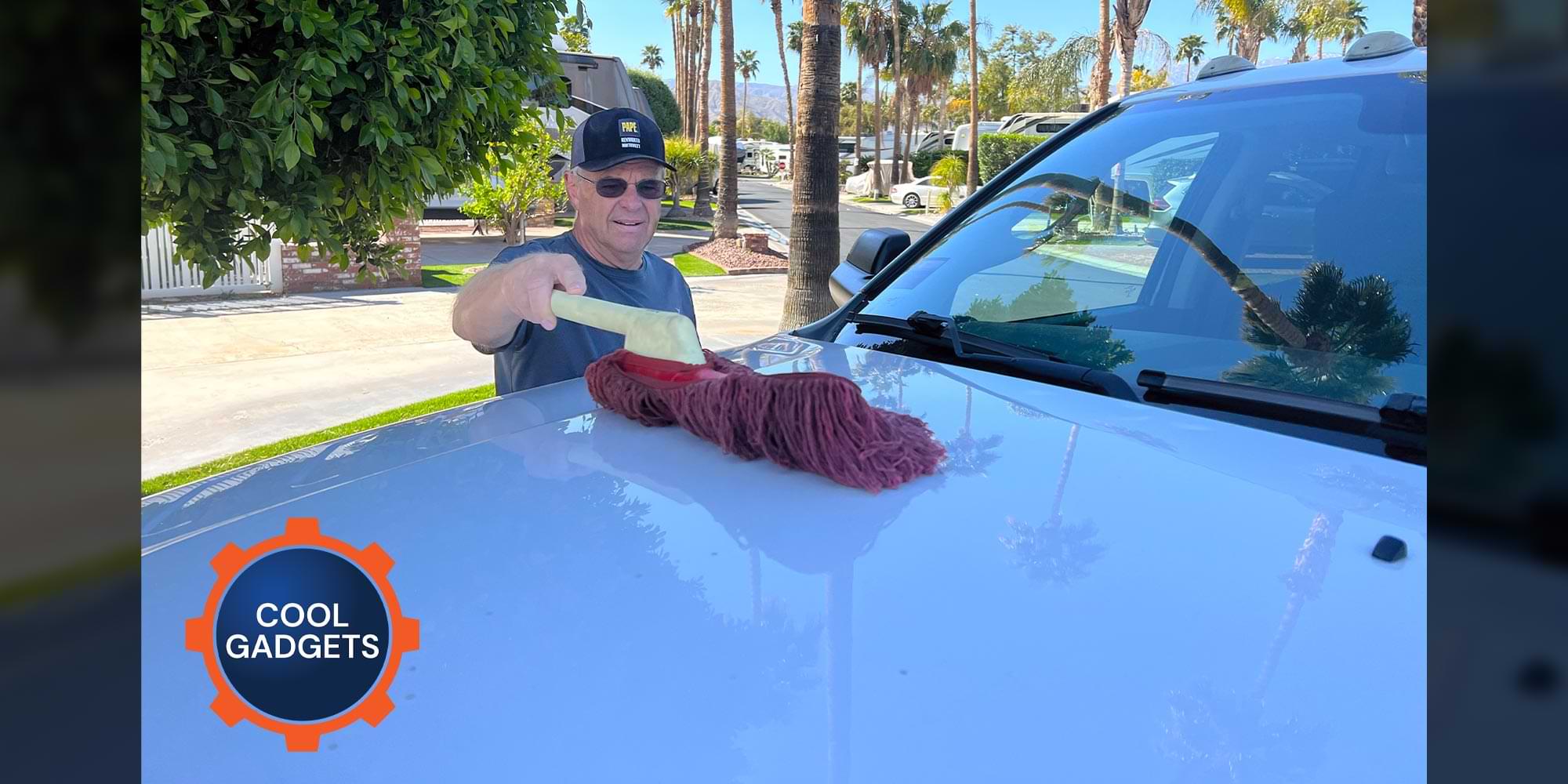 a man uses the California Car Duster on the hood of a white truck