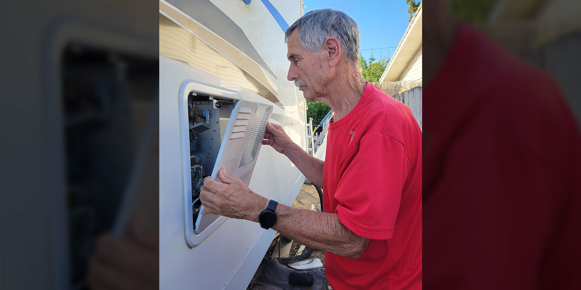 an RV technician removes the covering of the AC heating system on the outside of an RV