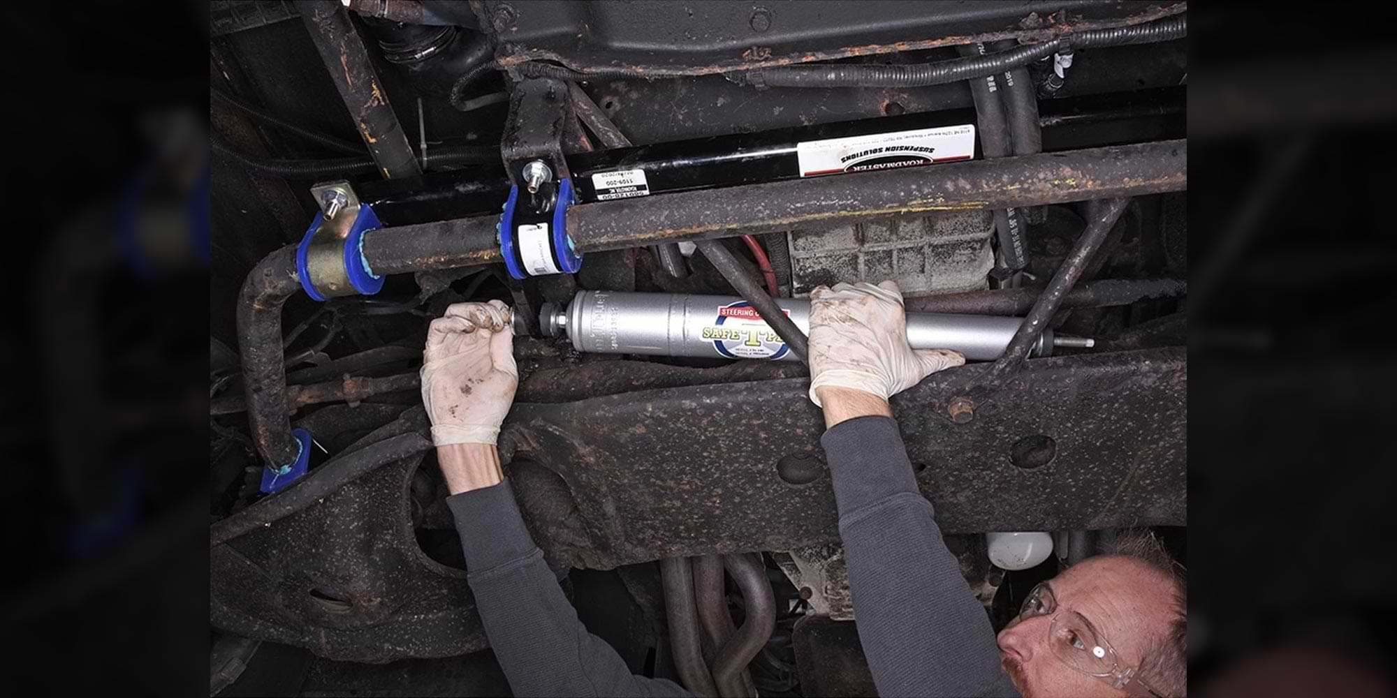 a technician installing a Safe T Plus steering control beneath a vehicle
