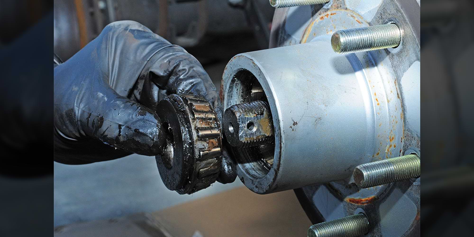 a latex gloved hand removes a wheel bearing component from an axle