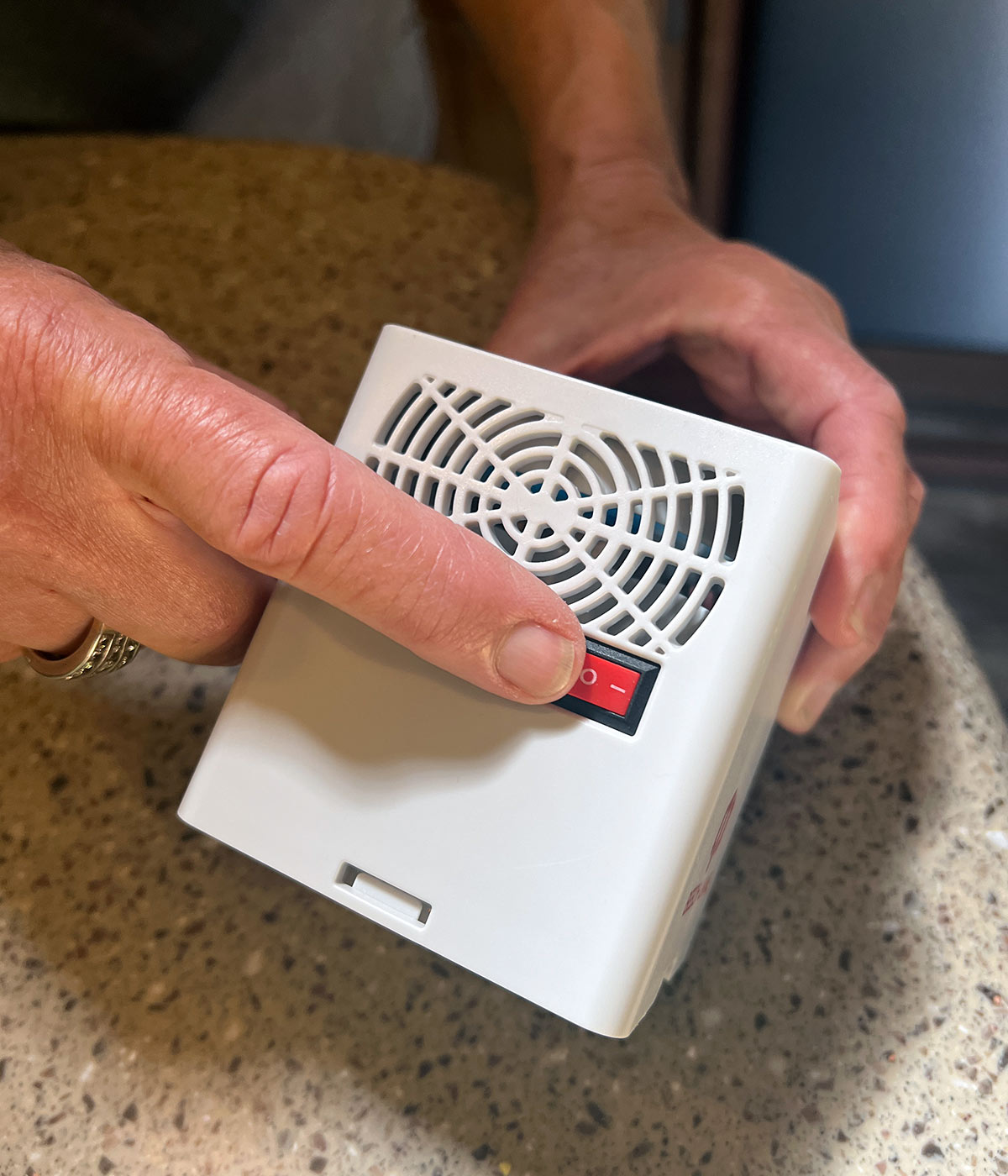 close view of the Fridge Fan as a finger points to the red power button on one side