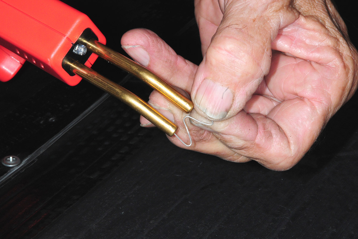 a hand holds a staple to the Wrdlosy Plastic Welder tubes