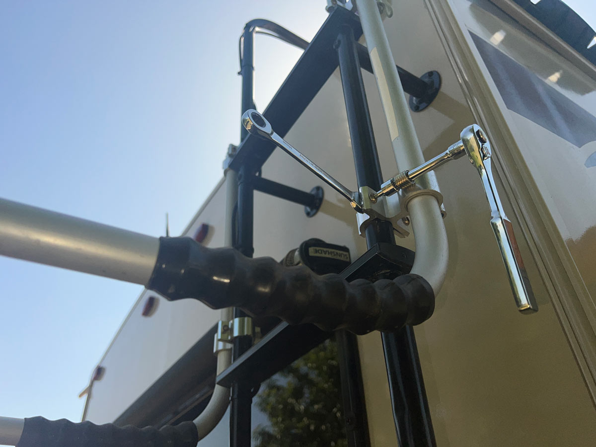 The arms in the Thetford ladder mount are attached to the handrails that connect to the rungs. The brackets are installed using the provided Allen wrench or ratchet/socket and a backing wrench for the locking nut.
