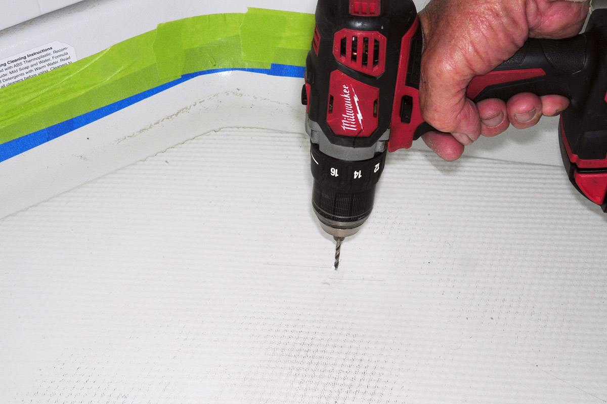 a drill is used to created holes in the cracked areas of the shower pan