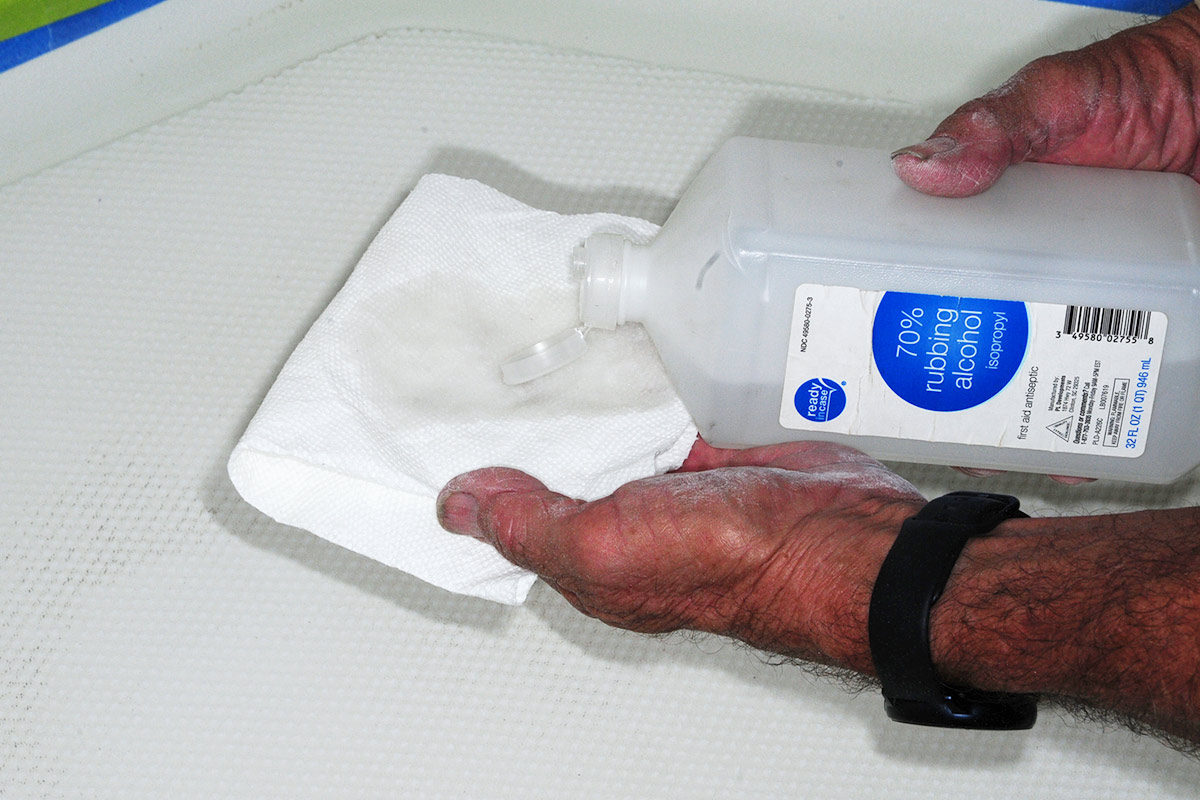 70% isopropyl rubbing alcohol is applied to a paper towel in a hand