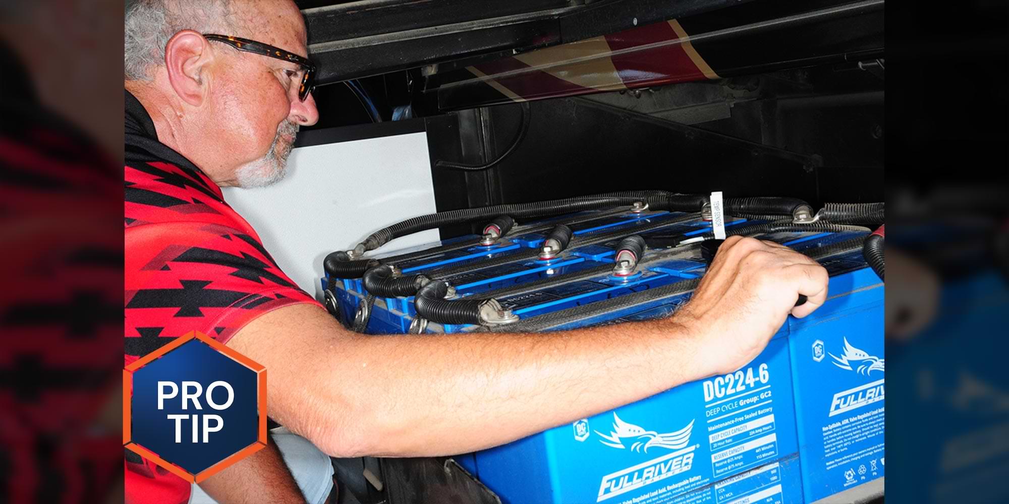 a man makes adjustments to a large RV battery group