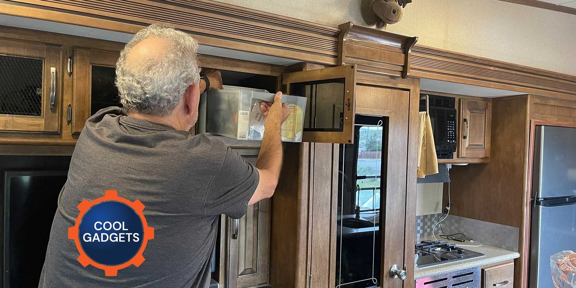 a man pushes a plastic drawer filled with items into an overhead RV cabinet