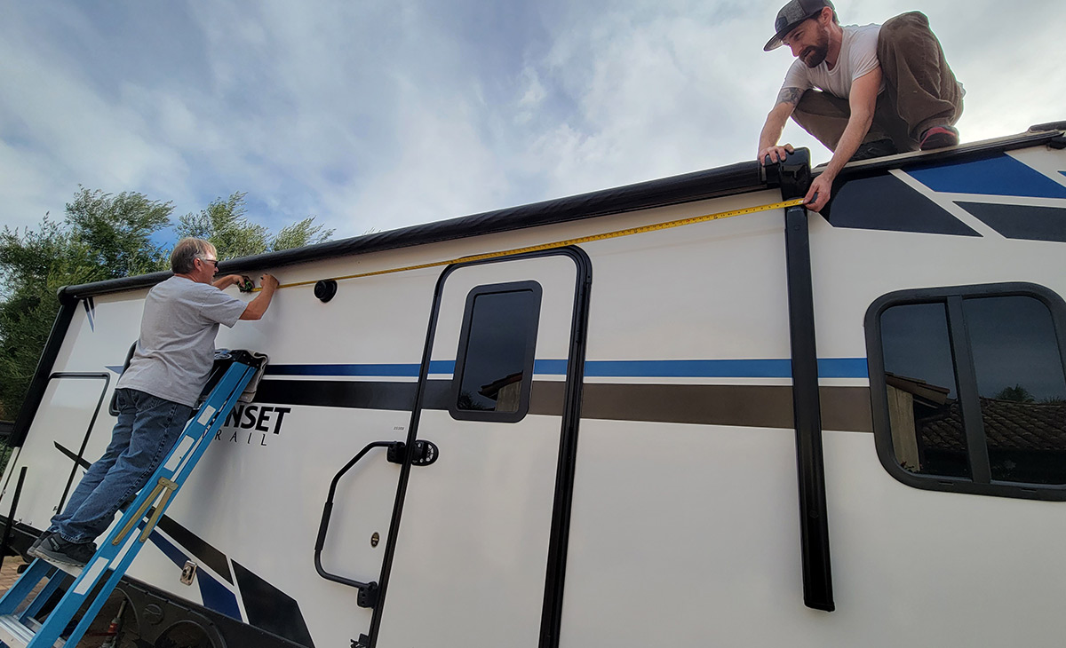 two men use measuring tape to locate the center of the awning tube