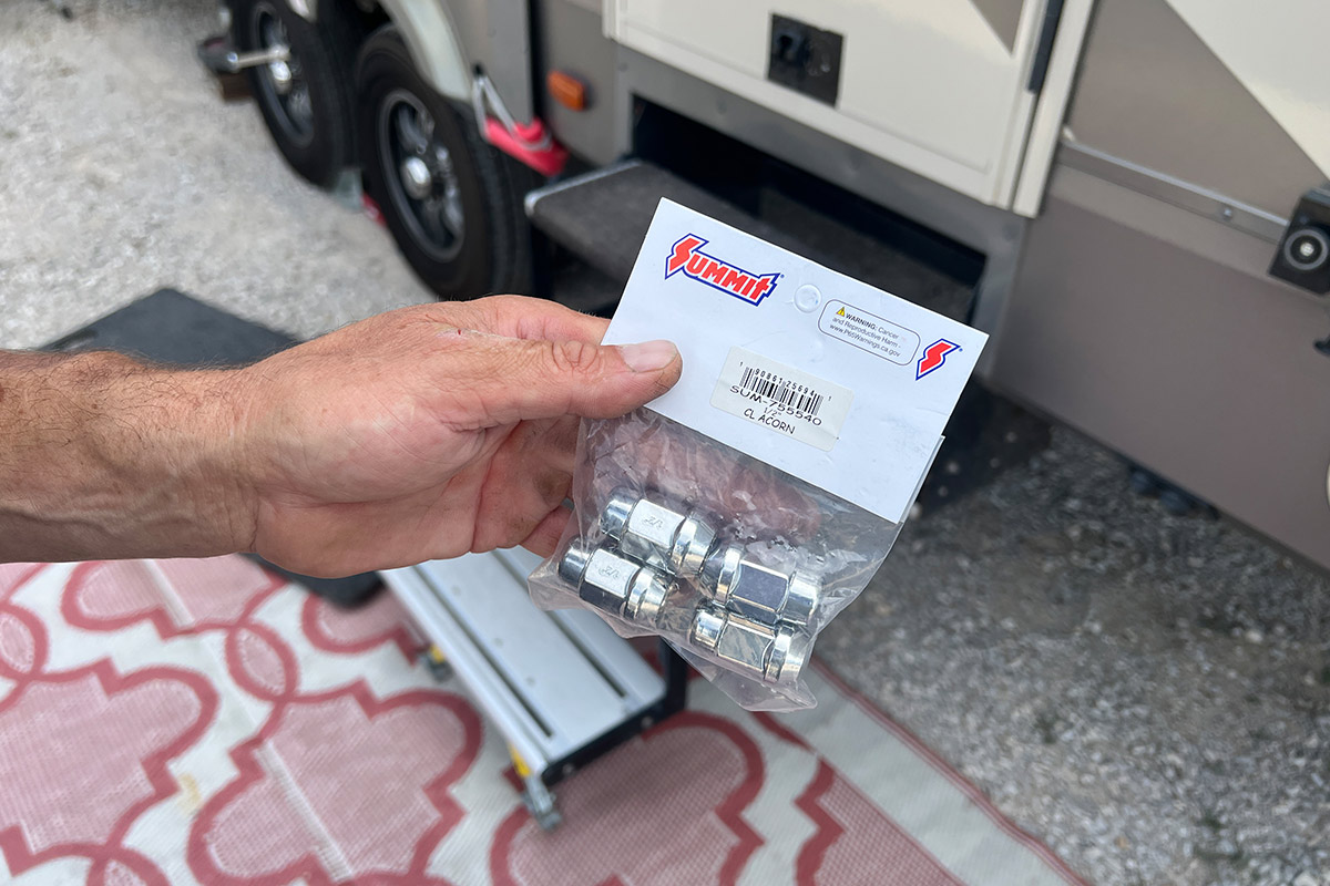 hand holds a package of ½-20 acorn-style lug nuts from Summit Racing